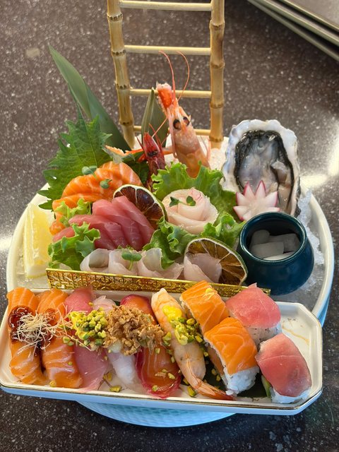 Barca di sushi a due piani: sopra sashimi misto, gamberi e ostrica, sotto un assortimento di nigiri e maki